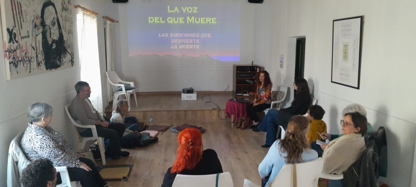 Una sesión del curso: el grupo, sentado en círculo, mira una proyección titulada «La voz del que muere»